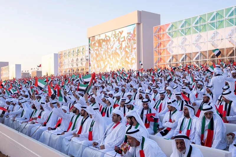Massive spectator grandstand filled with Emirati attendees facing high-definition LED broadcast screen in Al Wathba