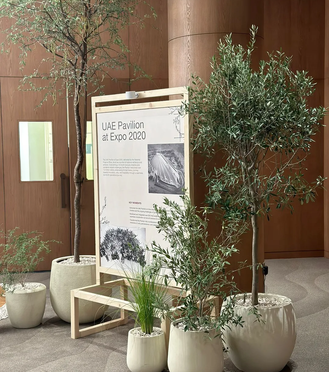 UAE Pavilion at Expo 2020 information display surrounded by potted trees and natural greenery