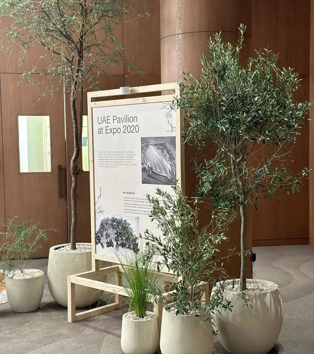UAE Pavilion at Expo 2020 information display surrounded by potted trees and natural greenery