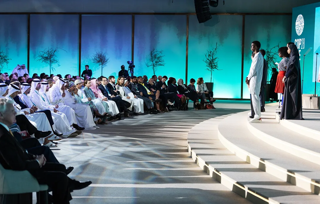Pre-COP28 main auditorium with a panoramic stage reflecting desert and ocean landscapes