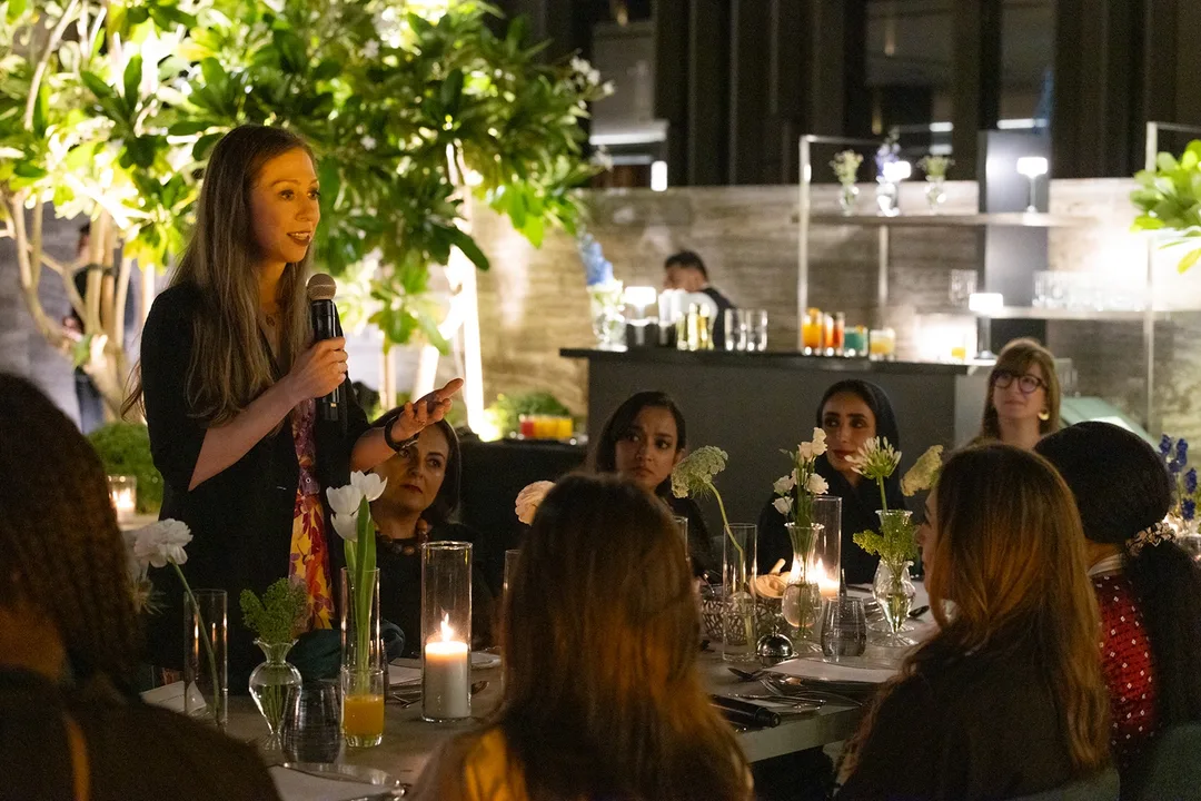A teal-toned dinner and networking environment shaped through elegant furniture, delicate florals and candlelight to support meaningful exchange.