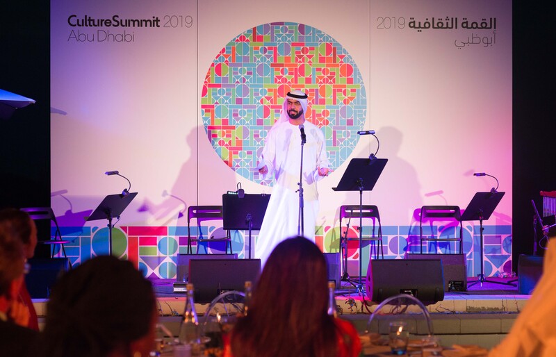 An image of a Arabic man on stage performing a spoken word piece