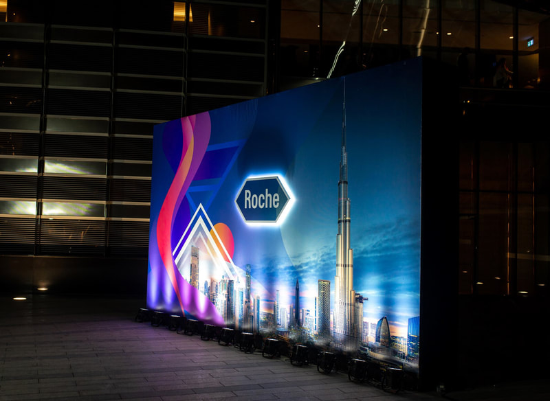 A lit branding wall featuring the Roche brandmark and the Burj Khalifa, uplit